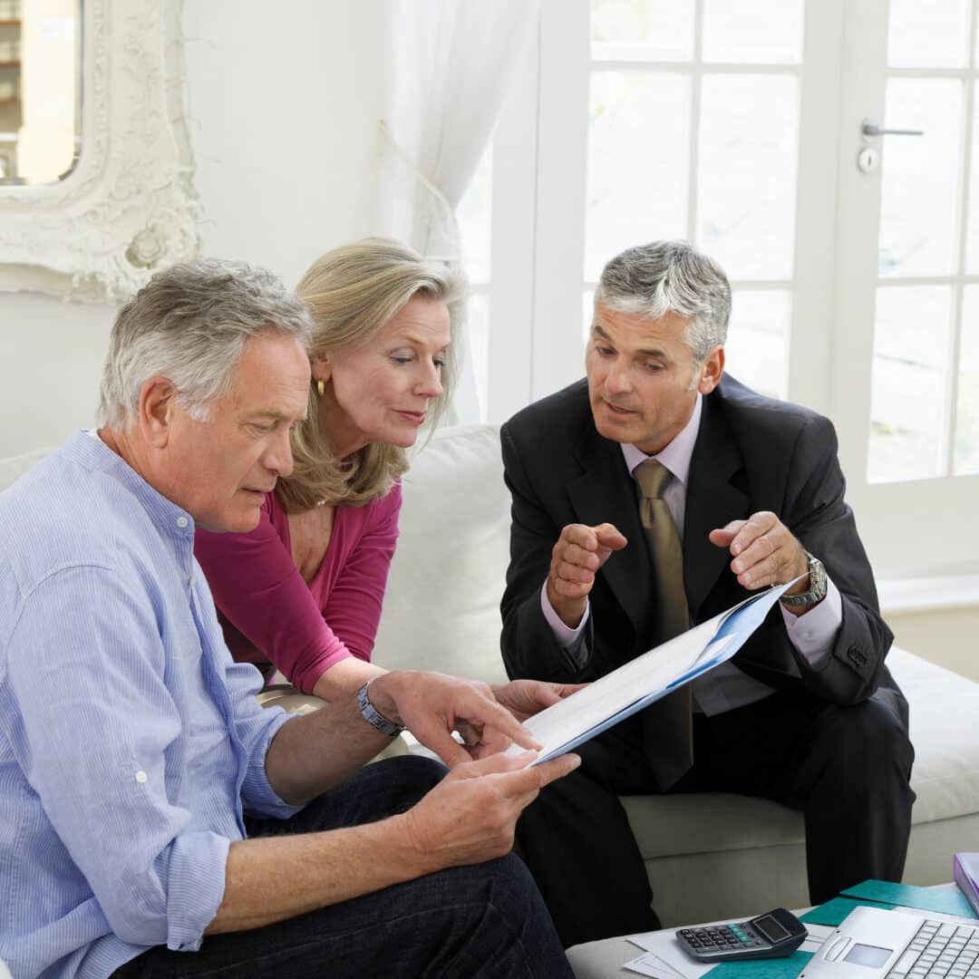 Mature couple sitting on sofa with financial advisor