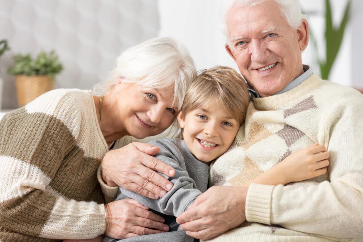 Loving grandparents cuddling on a couch with teenage grandson