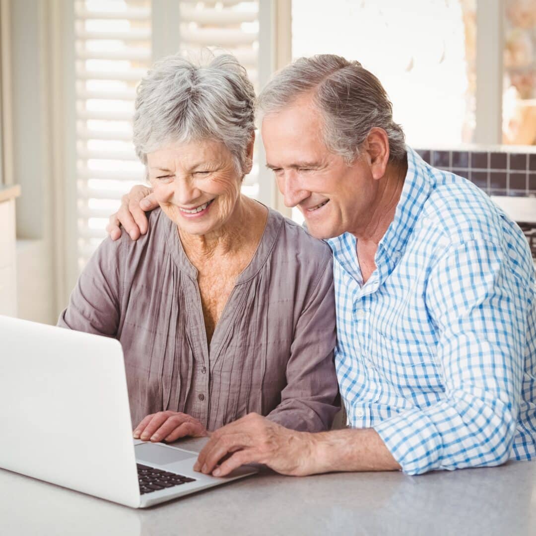 Cheerful senior couple using laptop