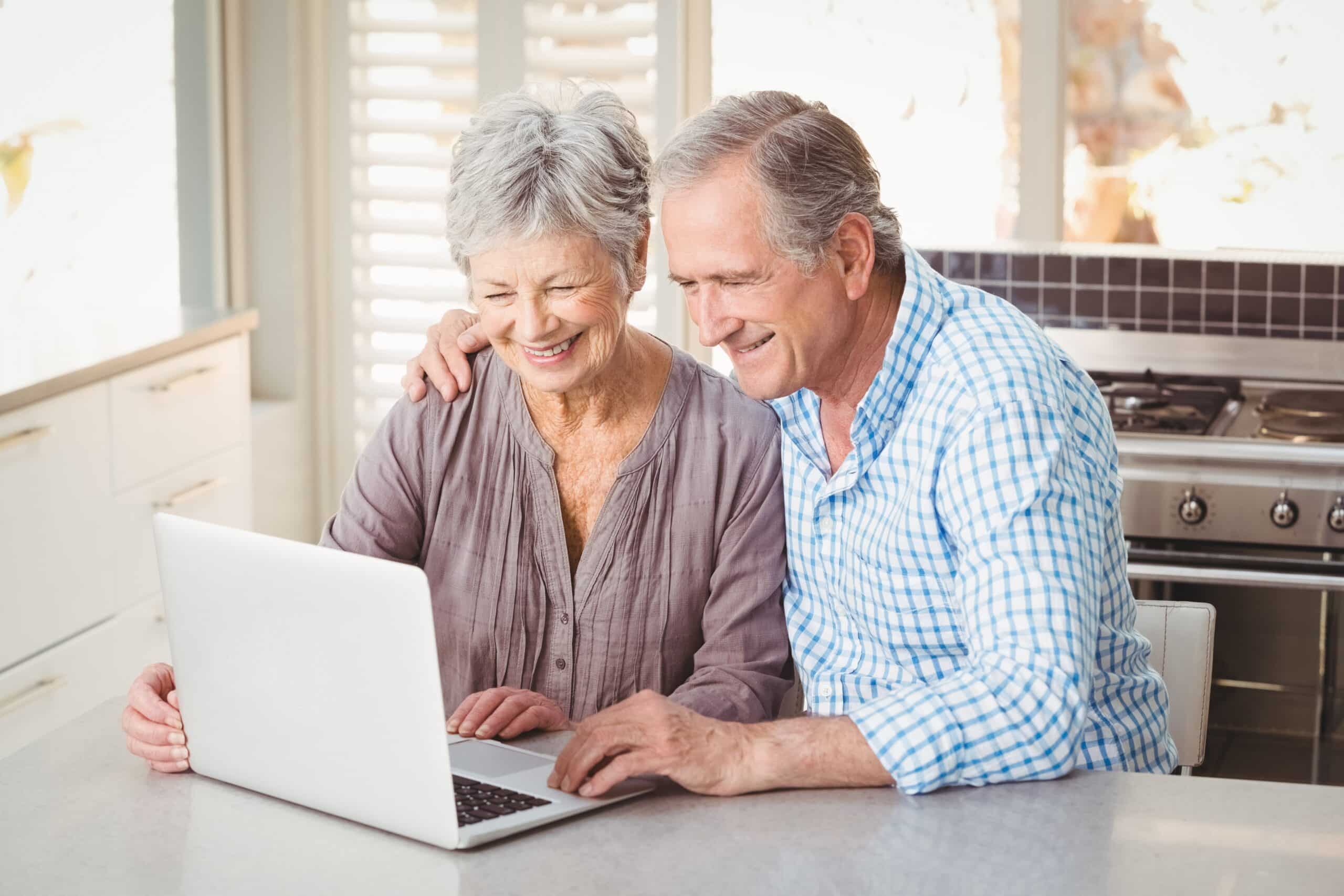 Cheerful senior couple using laptop