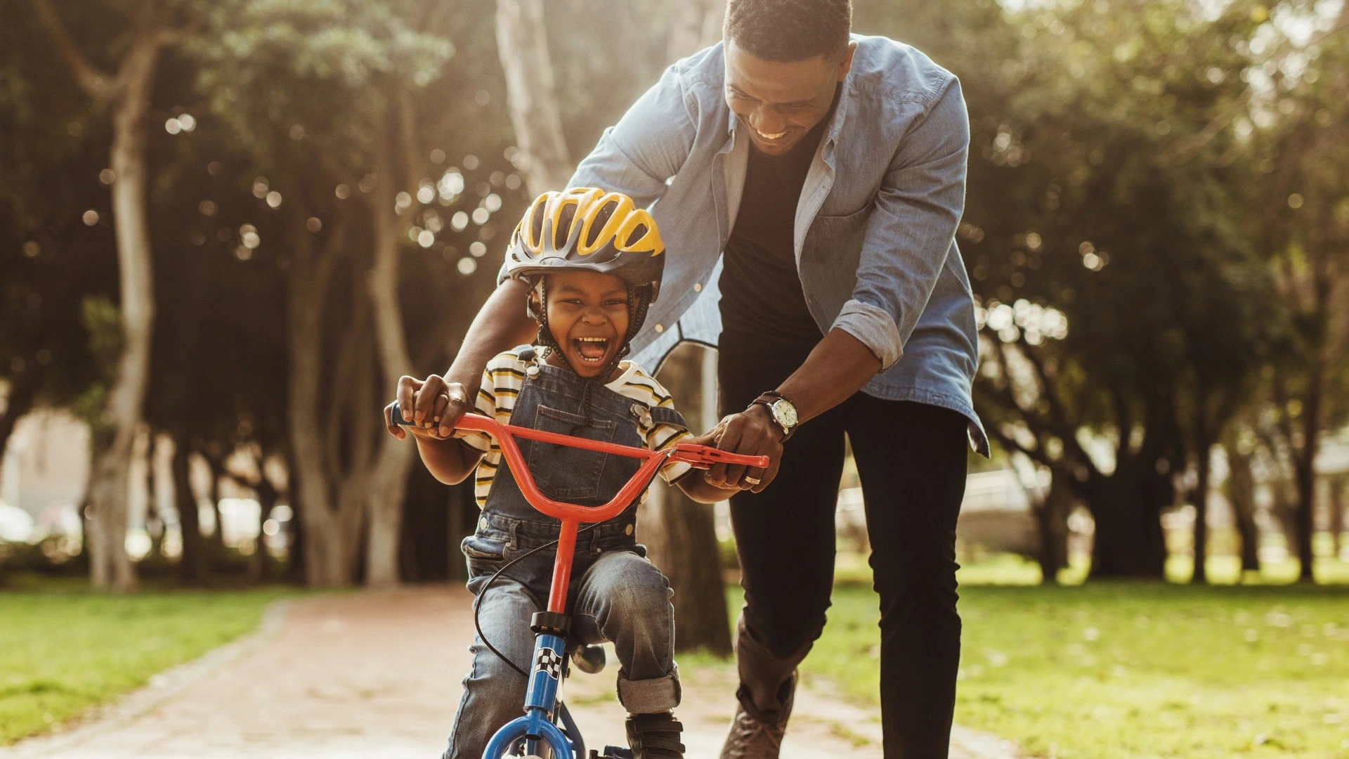 Man helping a child learn to ride a balance bike